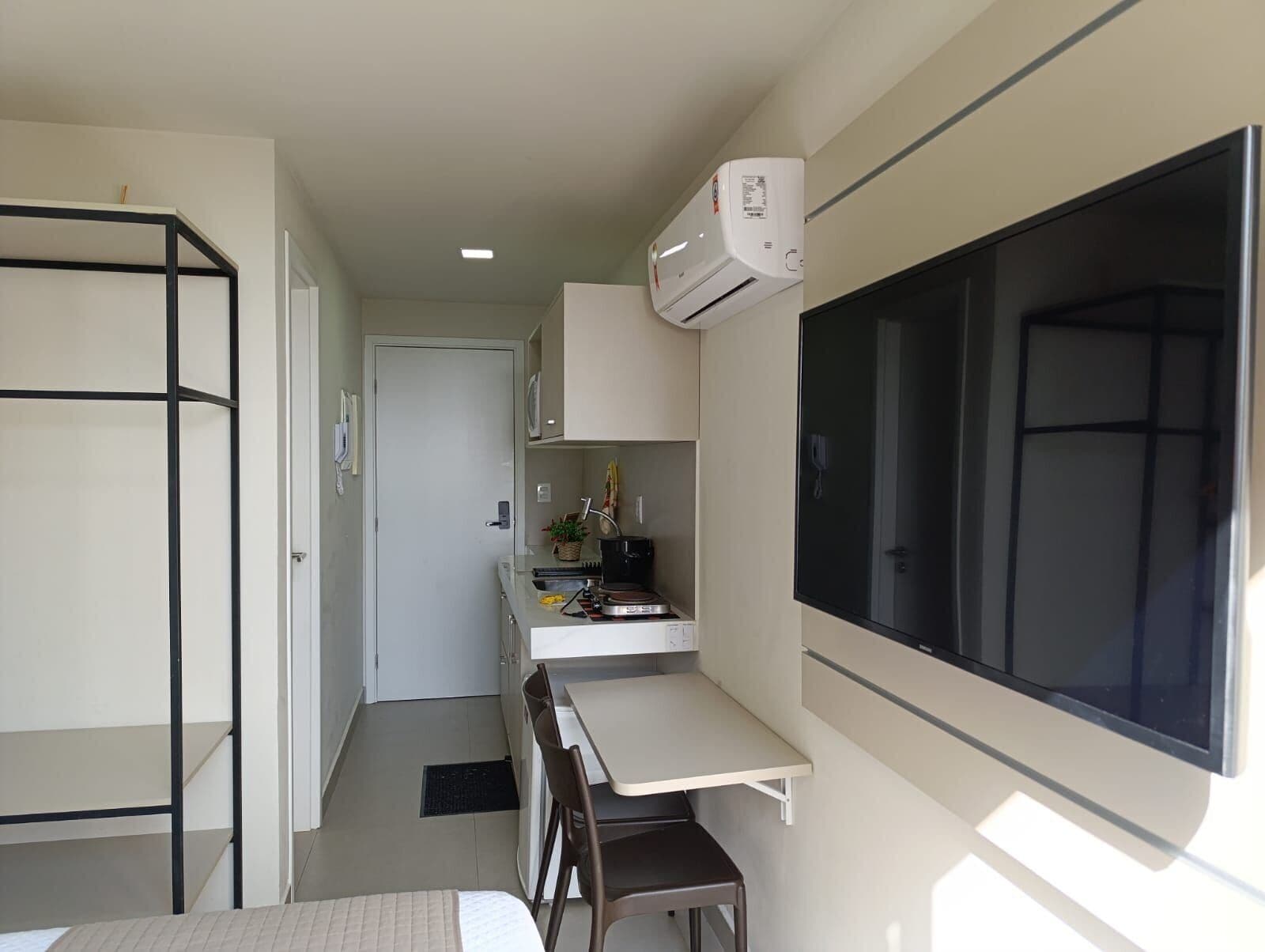 A compact kitchen with a dining area, a large window, and a built-in air conditioning unit.
