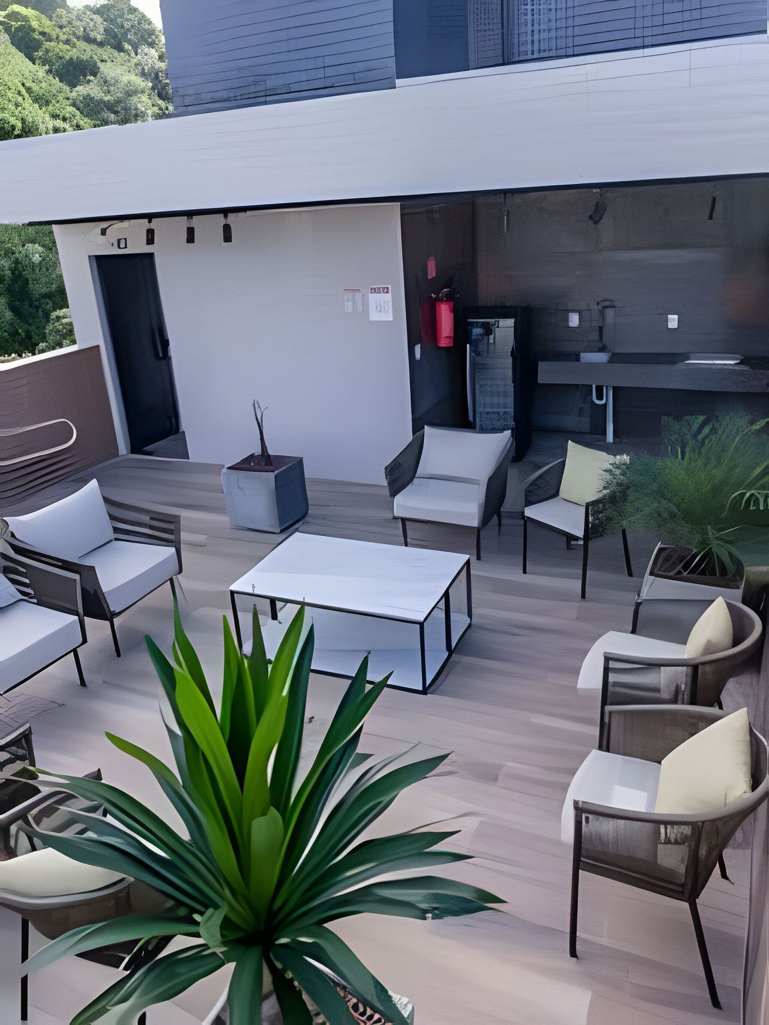 Un patio en la azotea con mobiliario exterior, una mesa y una planta en maceta.