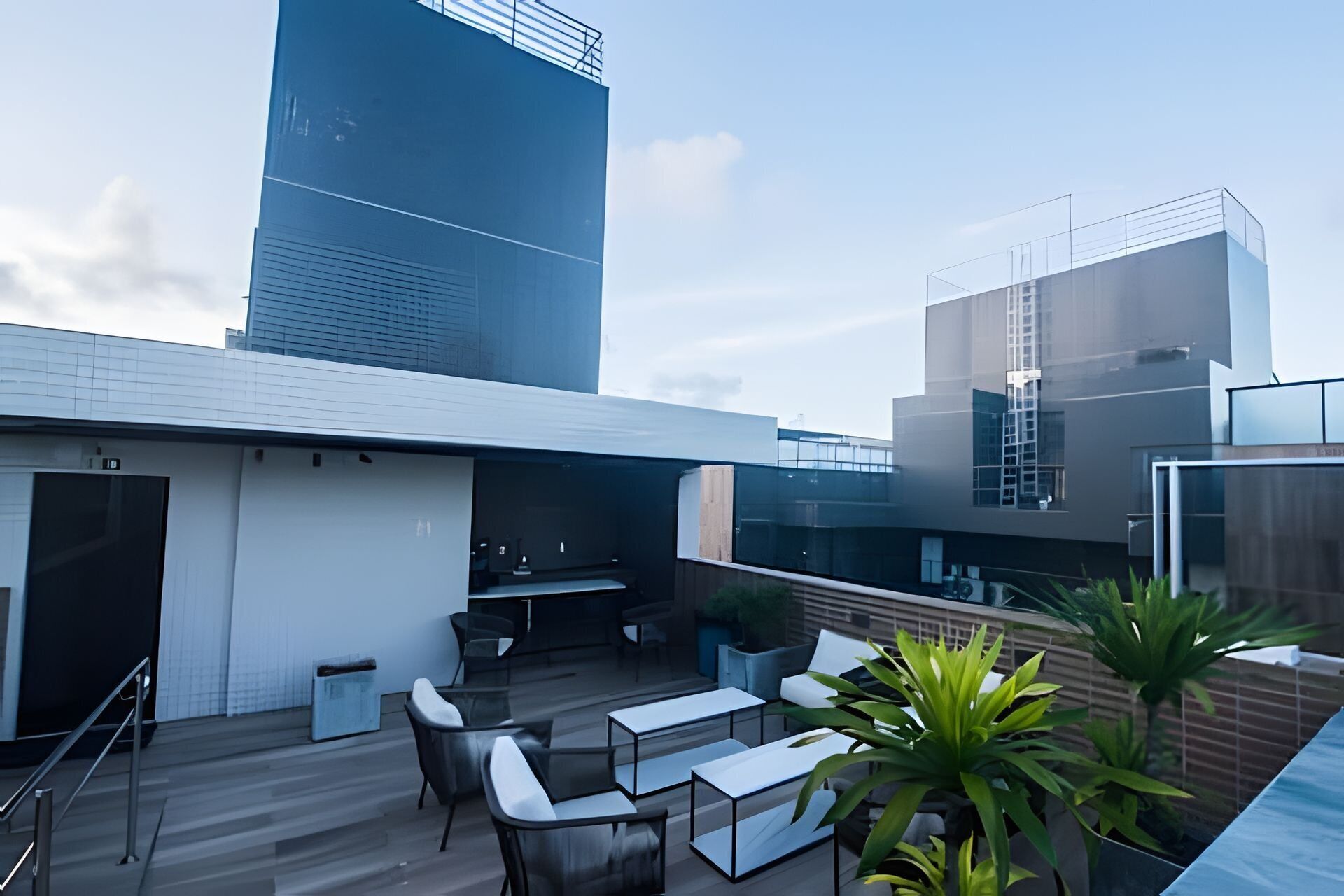 A rooftop terrace with outdoor seating, a small bar area, and views of surrounding buildings.