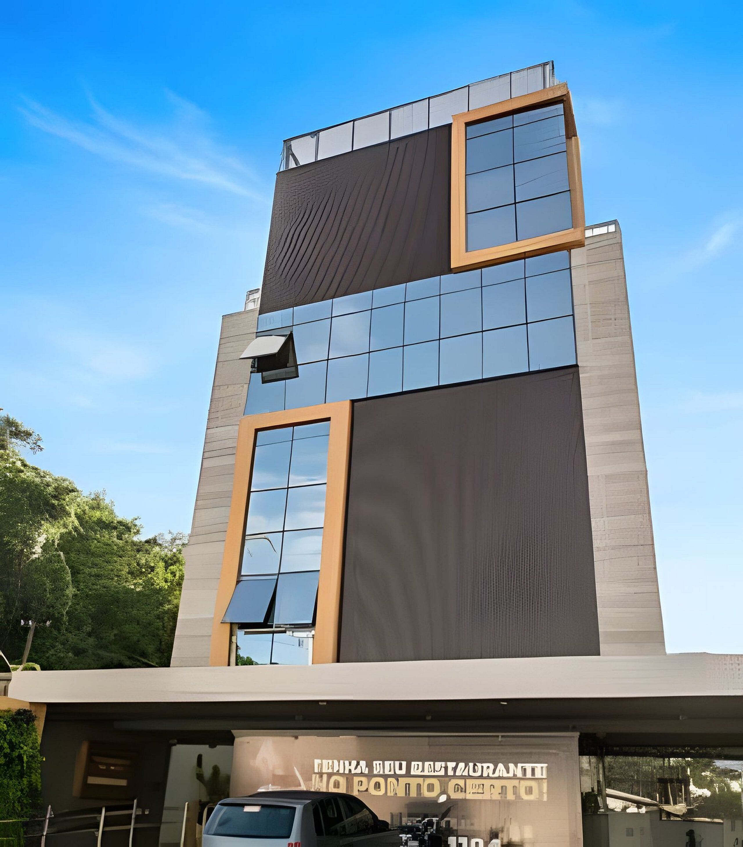 A modern building with a glass facade, a sign indicating a restaurant, and a clear blue sky.