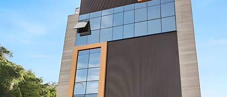 A modern building with a glass facade, a sign indicating a restaurant, and a clear blue sky.
