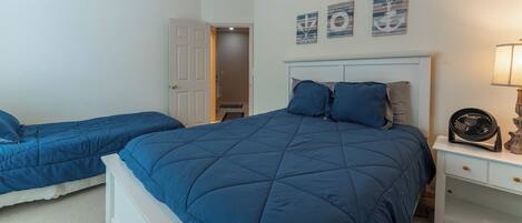 Quarto com duas camas, mesa de cabeceira, abajur e decoração na parede.