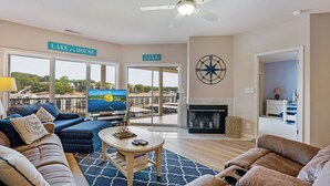 Una sala de estar con televisor, sofás, chimenea y un balcón con vistas al lago.