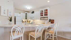 Una cocina con armarios blancos, una isla central con taburetes de bar y un microondas sobre la isla.