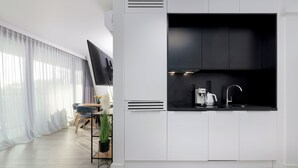A modern kitchen with white cabinets, a black countertop, and a built-in stove. - Wavescape - Wave Resort & Spa (Międzyzdroje)