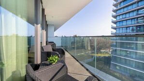 A balcony with wicker furniture and a glass railing overlooking a cityscape. - Wavescape - Wave Resort & Spa (Międzyzdroje)