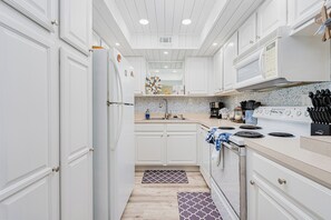 A modern kitchen with white cabinetry, a stainless steel range, and a patterned backsplash. - Aquarius Condo - Oceanfront #405 (Ormond Beach)