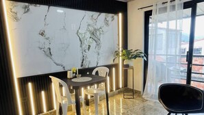 A modern living room with a marble wall, a dining area with a table and chairs, a blue sofa, and a large window with curtains. - Luxury Aparment in Chinacota With Studio Perfect for Remote Work (Chinacota)