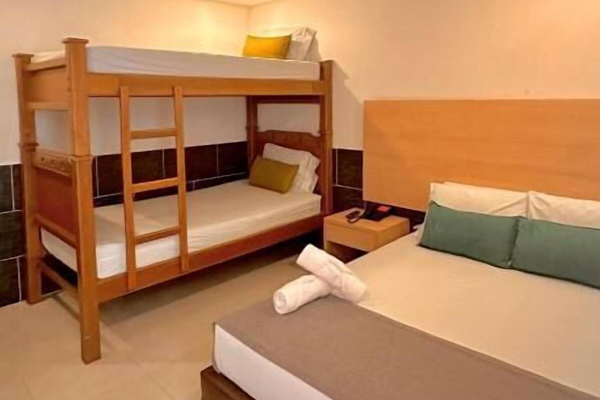 A bedroom with a bunk bed, a single bed, and a nightstand with a lamp.