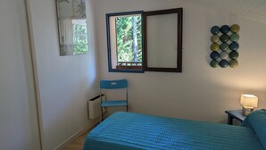 Une chambre à coucher comprenant un lit, une chaise, une fenêtre, un miroir et un luminaire fixé au mur.