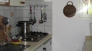 Une cuisine équipée d’une cuisinière, d’un four à micro-ondes et de divers ustensiles accrochés au mur.