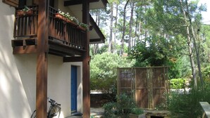 Un balcon en bois orné de jardinières, une porte bleue et un vélo.
