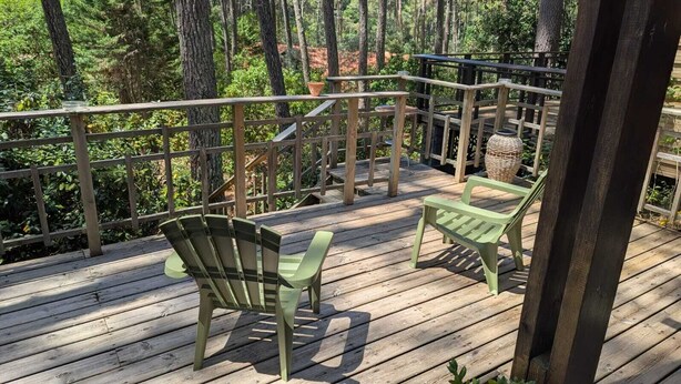 Une terrasse en bois avec deux fauteuils Adirondack et un panier en osier.