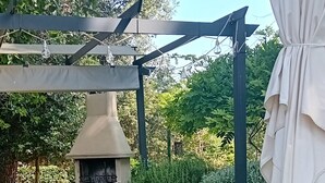 Um pátio com churrasqueira, mesa, cadeiras e uma pérgola.