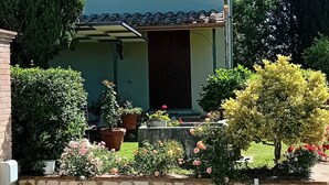 Uma casa de dois andares com fachada de pedra, telhado de telhas e uma pequena varanda com plantas em vasos.