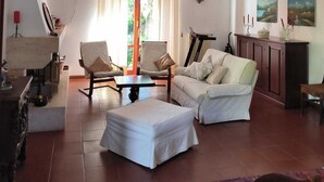 Uma sala de estar com sofá, cadeiras, mesa de centro, tapete e armário.