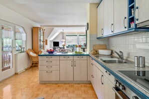 Une cuisine dotée d’un îlot central, de meubles en bois, d’un four encastré et d’une grande fenêtre.