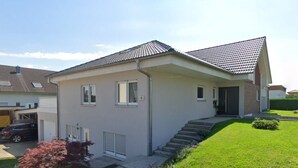 A single-story house with a tiled roof, a front entrance with steps, and a small front yard with a pathway and a bush. - Gerdes family vacation apartment in Waldenburg - good living in a quiet location (Waldenburg)