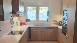 A compact kitchen with a window, a built-in oven, and a sink. - Gerdes family vacation apartment in Waldenburg - good living in a quiet location (Waldenburg)