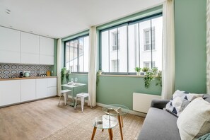 Une cuisine moderne avec des meubles blancs, une petite table à manger avec deux chaises et une table basse en verre.