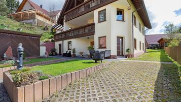 A two-story house with a balcony, a paved driveway, and a well-maintained lawn.