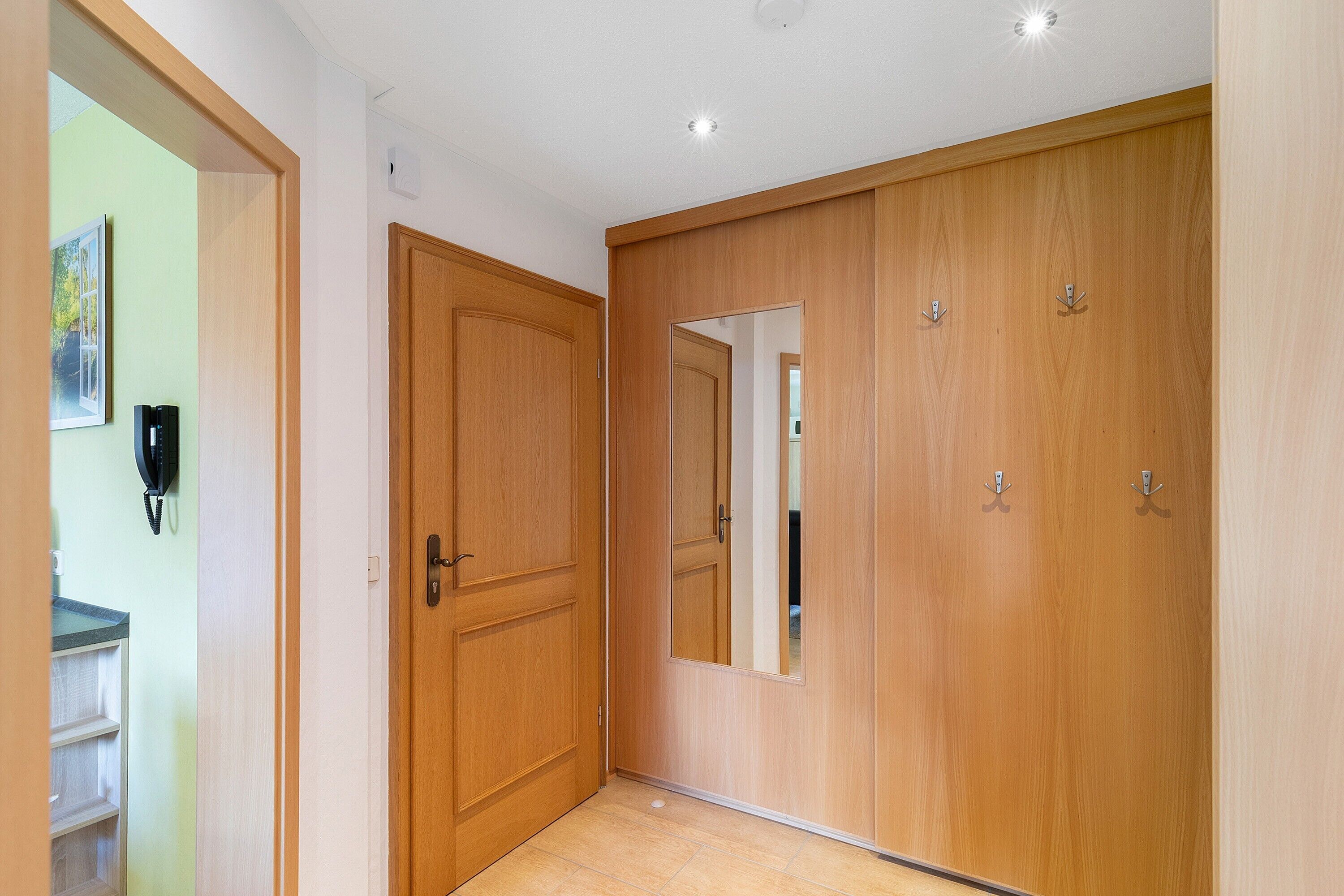 A hallway with wooden doors, a mirror, and a telephone.