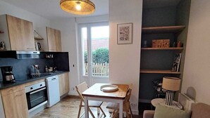 Ett kompakt bostadsutrymme med ett litet kök, en matplats och en sittgrupp.