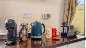 Un plan de travail de cuisine avec une machine à café, une bouilloire et des tasses à café.