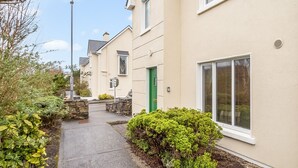 Une rangée de maisons de ville avec une allée étroite, des murs en pierre et une porte verte.
