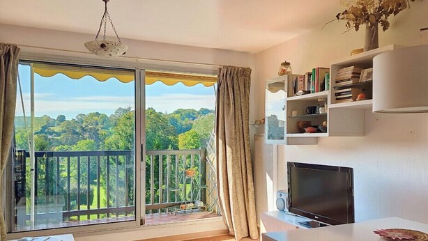 Una habitación con balcón, televisión de pantalla plana, estantería y mesa de comedor.