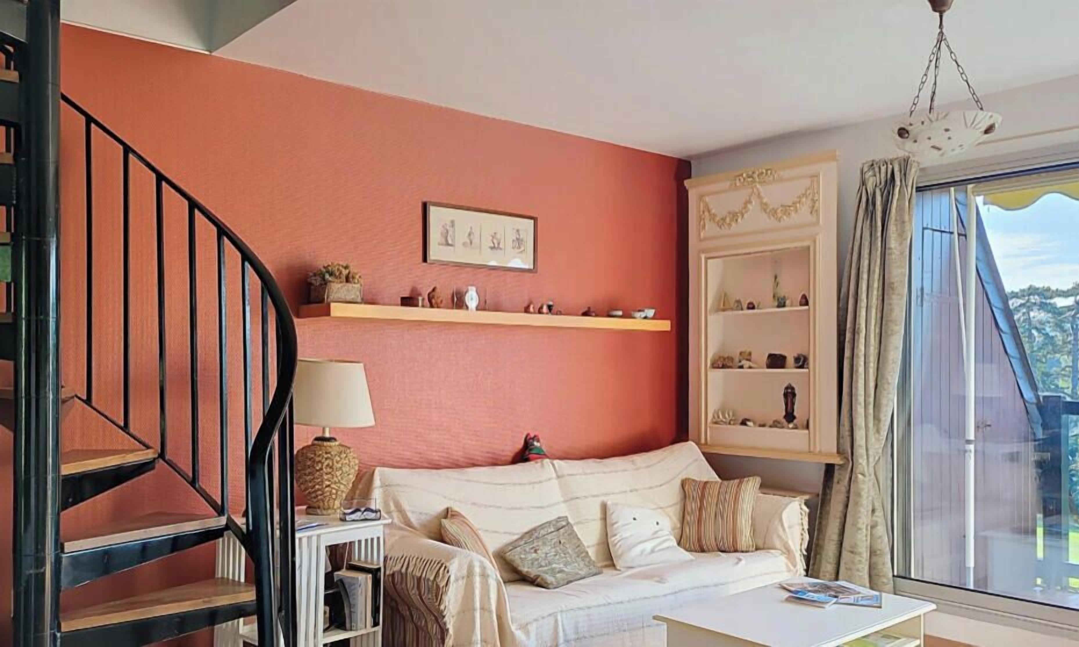 Una sala de estar con una escalera, un sofá, una mesa de centro y una estantería.
