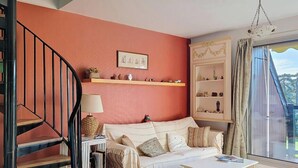 Una sala de estar con una escalera, un sofá, una mesa de centro y una estantería.