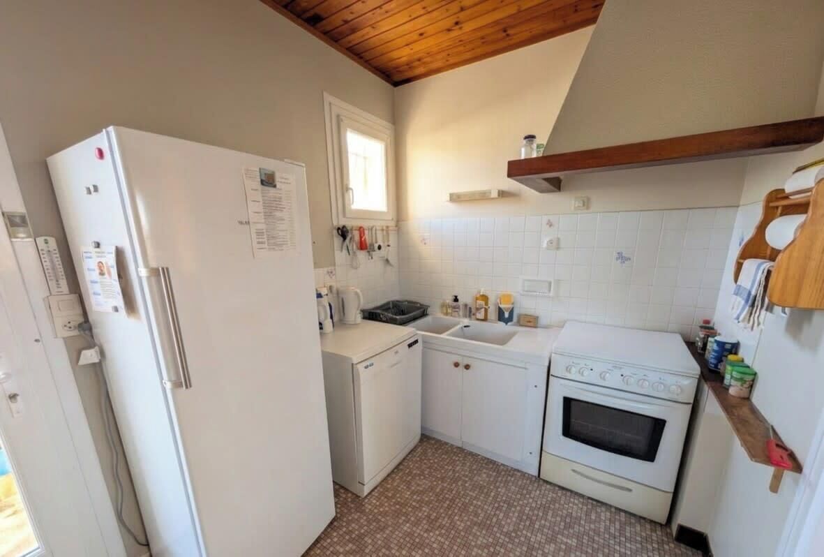 Una cocina compacta con refrigerador, lavadora pequeña, pileta y horno.