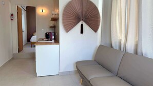 Ein kompakter Wohnraum mit einer Küchenzeile, einer Couch und einem dekorativen Wandventilator.
