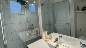 Ein modernes Badezimmer mit großem Spiegel, Duschkabine und Waschtisch mit Ablagefläche.