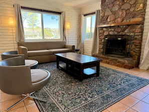 A living room with a stone fireplace, a sofa, a coffee table, and a patterned rug.