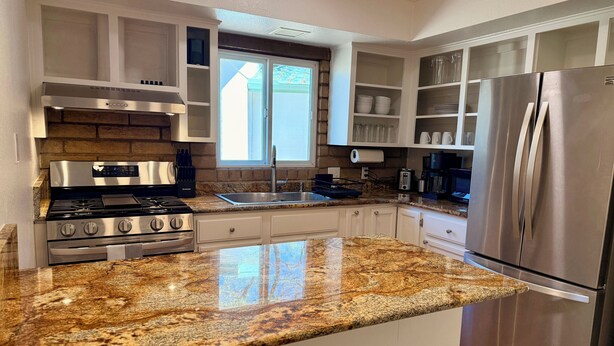 A kitchen with granite countertops, stainless steel appliances, and white cabinetry.