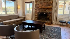 A living room with a stone fireplace, a sofa, a coffee table, and two armchairs.