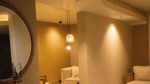 Une salle de bain moderne avec un grand miroir, un meuble-lavabo en bois, un tabouret rond et un luminaire suspendu.