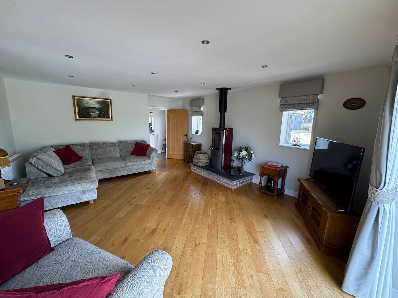 Una sala de estar con un sofá, televisor, chimenea y piso de madera.