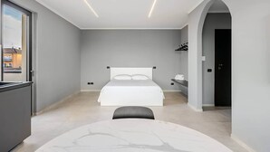 A modern hotel room with a bed, a desk, and a view through a window. - Brà Apartments & Lofts - Suite 1 | Verona Fiere (Verona)