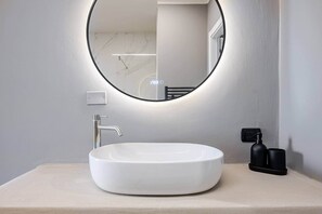 A bathroom with a round mirror, a white sink, and a towel rack. - Brà Apartments & Lofts - Suite 1 | Verona Fiere (Verona)