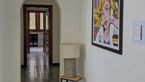 Un corridoio con una lampada, un quadro incorniciato e un pavimento piastrellato.