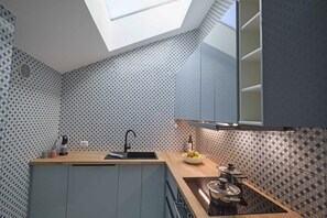 A compact kitchen with a skylight, patterned backsplash, and modern cabinetry. - Quiet lakefront apartment (GERA LARIO)