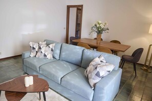 A living room with a sofa, a coffee table, a dining table with chairs, and a vase with flowers. - Quiet lakefront apartment (GERA LARIO)
