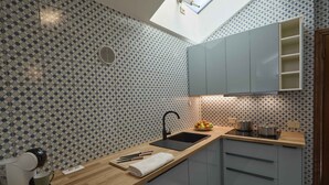 Una cocina con un salpicadero decorativo, tragaluces, un lavamanos, una cafetera y un frutero.