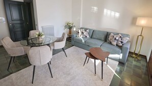 Una sala de estar con un sofá, dos sillones, una mesa de centro, una lámpara y una puerta.