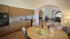 Una cucina moderna con mobili in legno, un piano di lavoro in marmo e una zona pranzo con un tavolo rotondo e sedie.