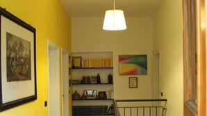 A hallway with a staircase, wooden flooring, a ceiling light, and a door leading to another room. - A large terrace overlooking the sea in the quiet of olive trees for families (Santa Giulia)