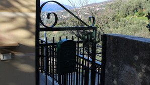 A gated entrance with a metal gate, a stone wall, and a view of a hilly landscape. - A large terrace overlooking the sea in the quiet of olive trees for families (Santa Giulia)
